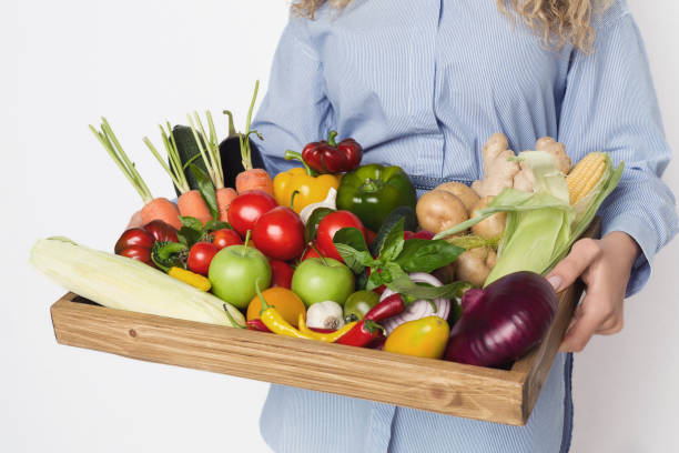 istock Female hands holding wooden board with various vegetables 1067483530