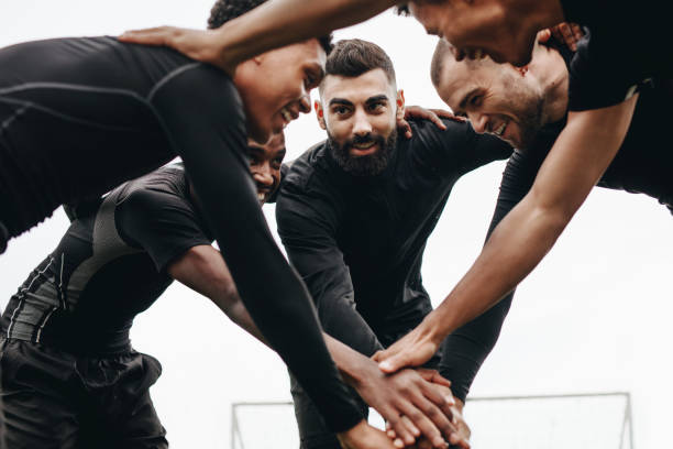 istock Soccer players joining hands standing in a huddle 1067489080