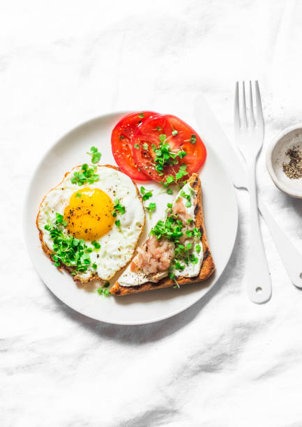istock Healthy breakfast or brunch - fried egg, fresh tomatoes and smoked mackerel toast on a light background, top view 1067491532