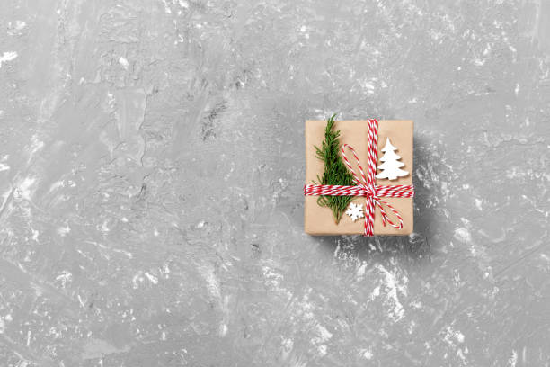 istock gift box wrapped in recycled paper, with ribbon bow, with christmas decor. Cement table background, copy space 1067501490