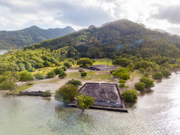 Ancient Marae Taputapuatea temple complex on the lagoon shore with mountains on background. Raiatea island. French Polynesia, Oceania. stock photo