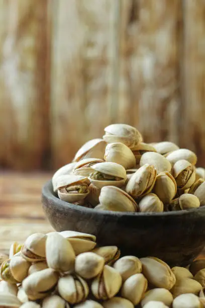 Bowl with pistachio on wooden table