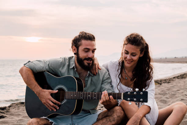 istock Young man playing acoustic guitar at the beach 1067506008