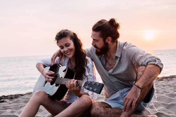 istock Young woman playing guitar at the beach 1067507216
