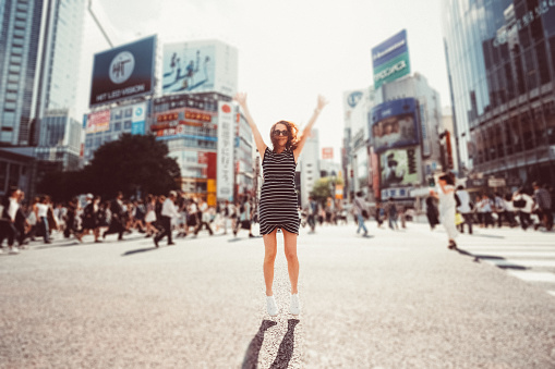 Tourist woman in Tokyo jumping with hands raised
