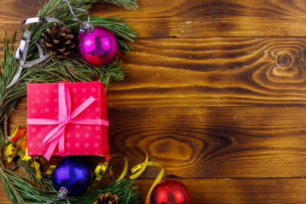 istock Christmas composition with fir tree branches, gift box and Christmas decorations on wooden table. Top view, copy space 1067514778