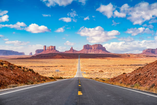 Long road at Monument Valley Utah side USA Stock photograph of long road leading towards Monument Valley as seen from Forrest Gump Point, Utah. monument valley stock pictures, royalty-free photos & images
