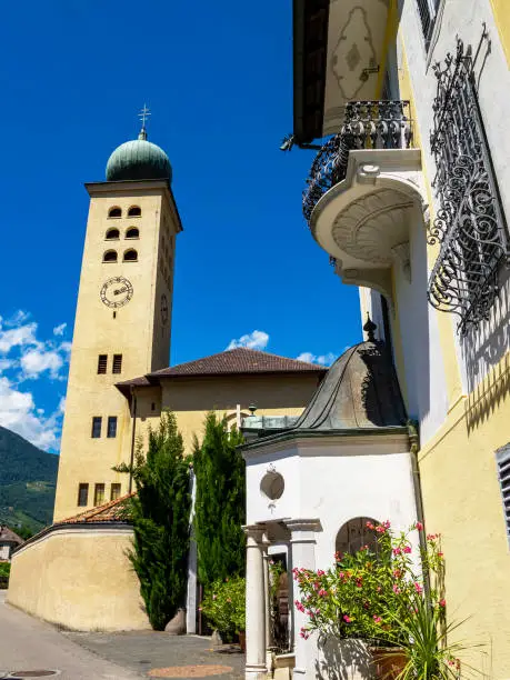 Bell tower of the Parish Church of the Holy Cross and part of the Deutschordenkonvent or the convent of the Teutonic Order in Lana, South Tyrol, Italy