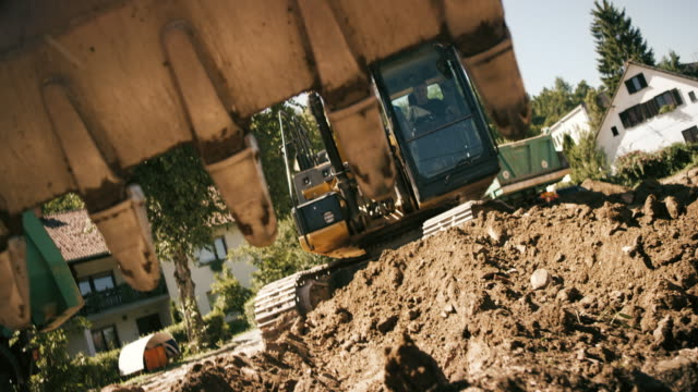 SLO MO Bucket on the excavator digging into the soil at the building site in sunshine