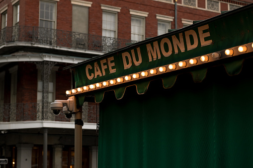 New Orleans, USA - Nov 6, 2018: The famous illuminated Cafe Du Monde awning late in the day with the Pontalba Buildings. The cafe is world renowned for its fluffy Beignets and Chicory coffee.