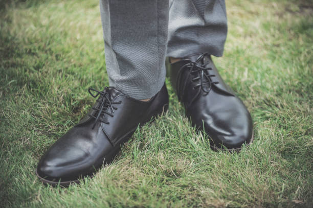 istock Low Section Of Man Wearing Leather Shoes While Standing On Grass 1067540572