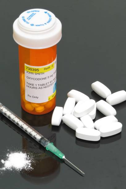 Narcotic medications (opioids) Vertical image of white tablets (pills), prescription vial with fake label for oxycontin, syringe with needle and white powder representing opioid (drug)crisis (epidemic) affecting America. fentanyl stock pictures, royalty-free photos & images