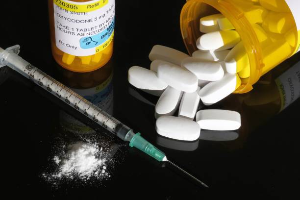 Narcotic drugs (opioids) Horizontal image of white tablets (pills), prescription vials with fake label for oxycontin, syringe with needle and white powder representing opioid (drug)crisis (epidemic) affecting America. fentanyl addiction stock pictures, royalty-free photos & images