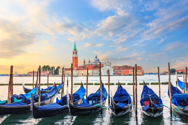 Gondolas moored at the pier in Grand Canal with San Giorgio Maggiore in the background, Venice, Italy Gondolas moored at the pier in Grand Canal with San Giorgio Maggiore in the background, Venice, Italy. gondola traditional boat photos stock pictures, royalty-free photos & images