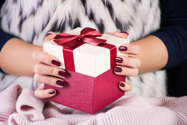 istock Girl holding red gift present box with tie bow in hands 1067552118