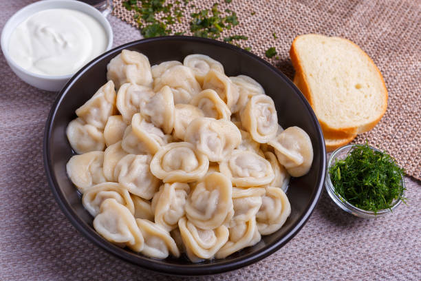 boiled dumplings national dish of many nations with sour cream, soy sauce and greens - fotografia de stock