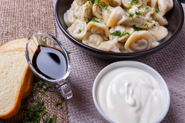 boiled dumplings national dish of many nations with sour cream, soy sauce and greens - fotografia de stock