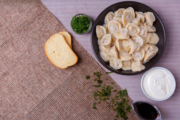 boiled dumplings national dish of many nations with sour cream, soy sauce and greens - fotografia de stock