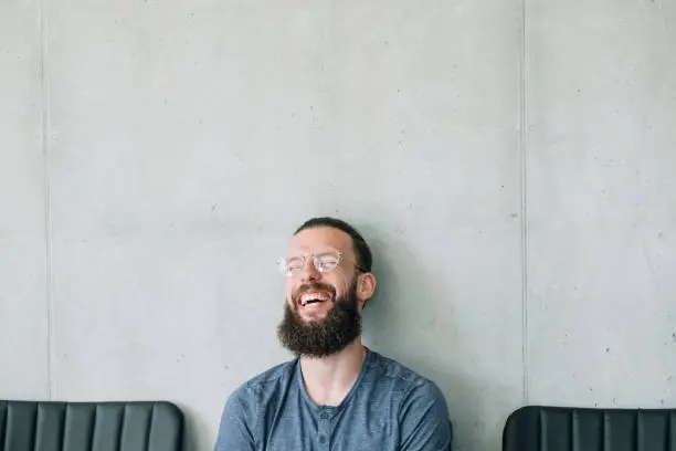 happy laughing bearded man in glasses. emotion expression