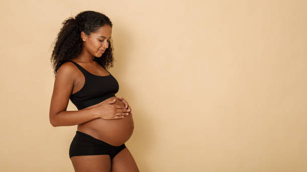 Studio shot of a pregnant woman looking on her belly, copy space stock photo