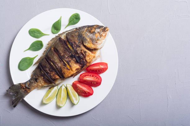 istock Fried fish dorado with lime , tomatoes and spinach 1067565756