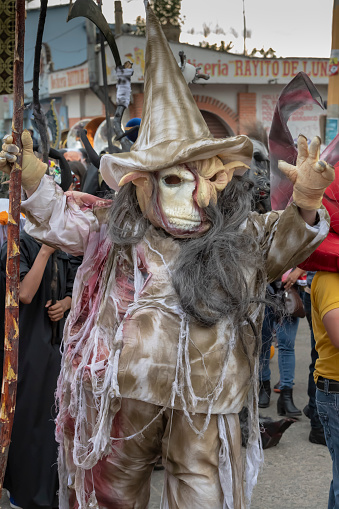 Xoxocotlán, Oaxaca, Mexico– November 1, 2018:  A person dressed as a hag or ghoul in a parade for the Día de los Muertos festival.  This annual holiday is celebrated extensively in southern Mexico with face painting, costumes, parades, dancing, altars, and graveside vigils. Celebration of the Día de los Muertos has been adopted in many other parts of the world.