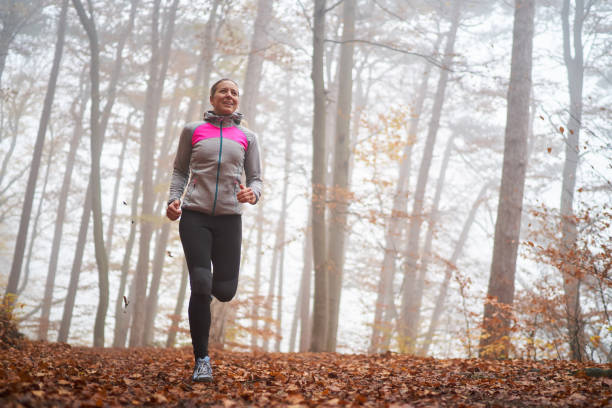 istock smiling female runner training in autumn forest fog behind trees 1067566908