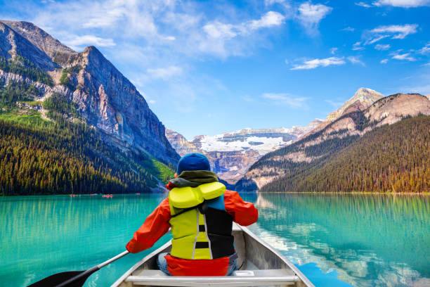 カナダのバンフ国立公園のレイク ・ ルイーズにカヌーの少年 - canoeing paddling canoe adventure ストックフォトと画像