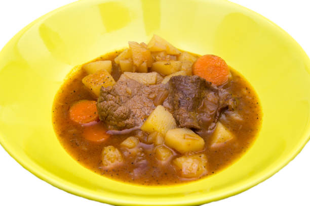 Stewed meat and vegetables on a white background seen close up