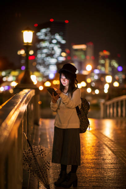 istock Woman texting on bridge at night 1067604284