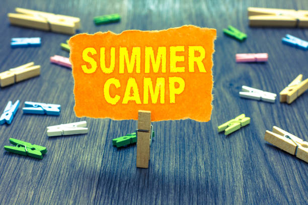 istock Conceptual hand writing showing Summer Camp. Business photo text Supervised program for kids and teenagers during summertime. Clothespin holding orange paper note clothespins wooden floor. 1067623594