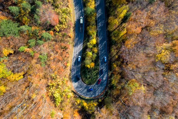 istock Traffic on Curvy Road Through Autumn Forest, Aerial View 1067625280