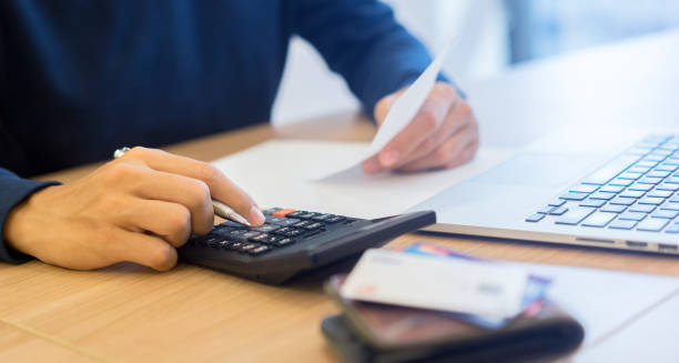 close up man hand press on calculator counting calculating about monthly expense from debt bill at the table in home office and managing payroll,money risk financial concept