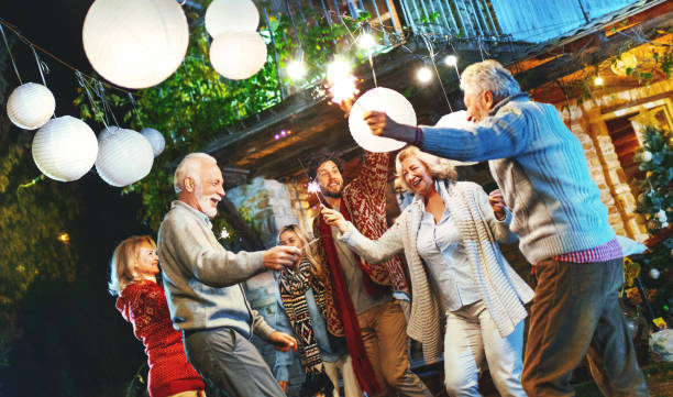 Backyard Thanksgiving party. Closeup of group of mixed age people having a backyard party after Thanksgiving dinner. They are dancing and having some champagne. Usable for Christmas/New year's. lanterns at night stock pictures, royalty-free photos & images