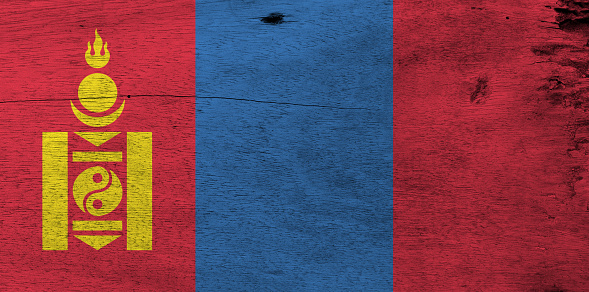 Flag of Mongolia on wooden plate background. Grunge Mongolian flag texture, red and blue with the Soyombo symbol centred on the hoist-side of the red band.