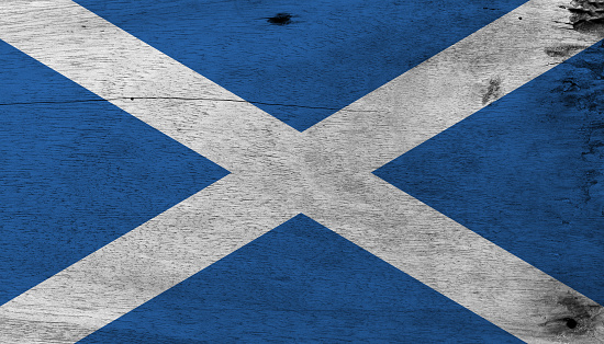 Flag of Scotland on wooden plate background. Grunge Scotland flag texture, it is a blue field with a white diagonal cross that extends to the corners.