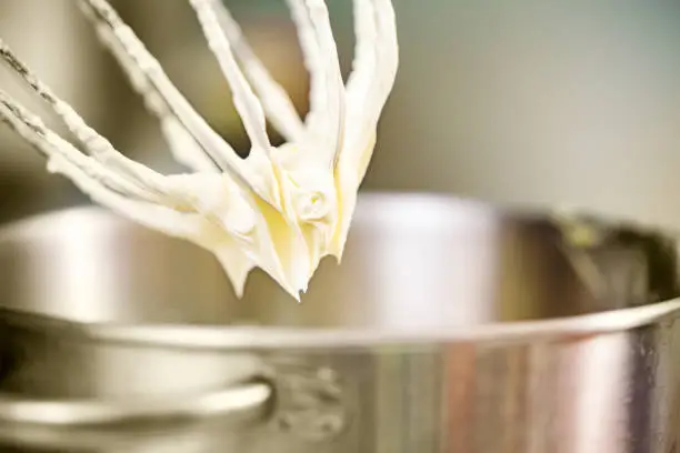 Whipped cream hanging on electric mixer's whip