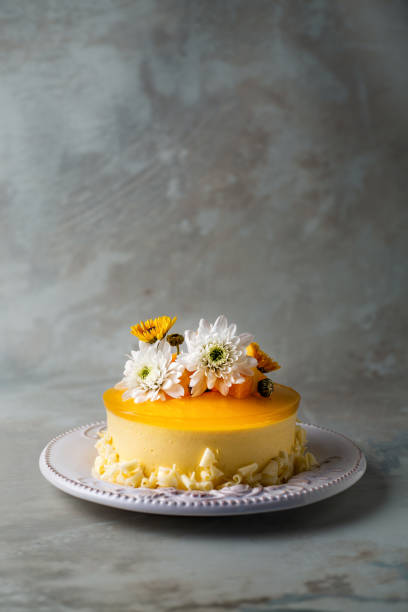 istock Glazed Mango cheesecake with flowers and fresh mango pieces on grey background , vertical composition 1067694522