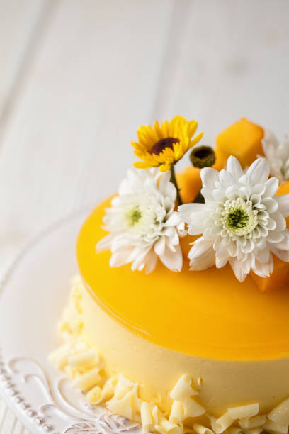 istock Glazed Mango cheesecake with flowers and fresh mango pieces on grey background , vertical composition, close up 1067694590