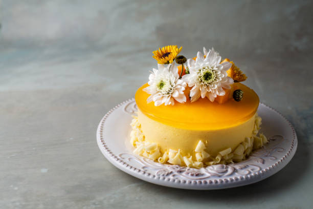 istock Glazed Mango cheesecake with flowers and fresh mango pieces on grey background 1067694600