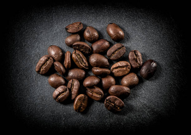 gros plan des grains de café torréfiés sur fond noir - black coffee coffee macro cafe photos et images de collection