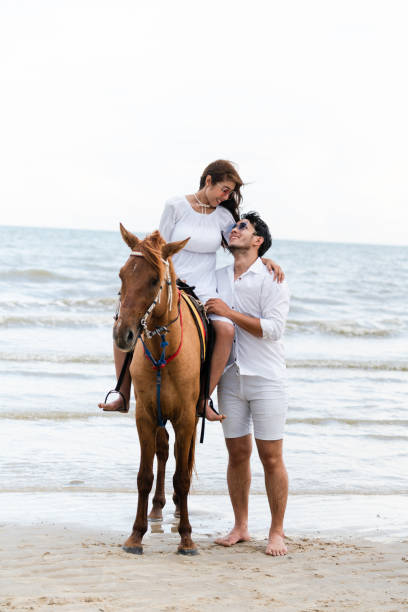 istock Young couple goes horse riding on tropical beach. 1067710014