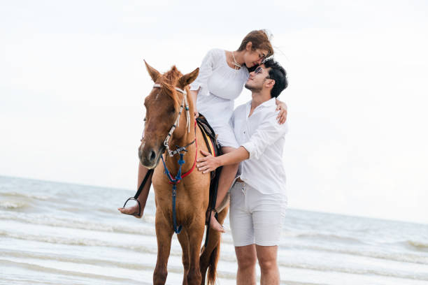 istock Young couple goes horse riding on tropical beach. 1067710028