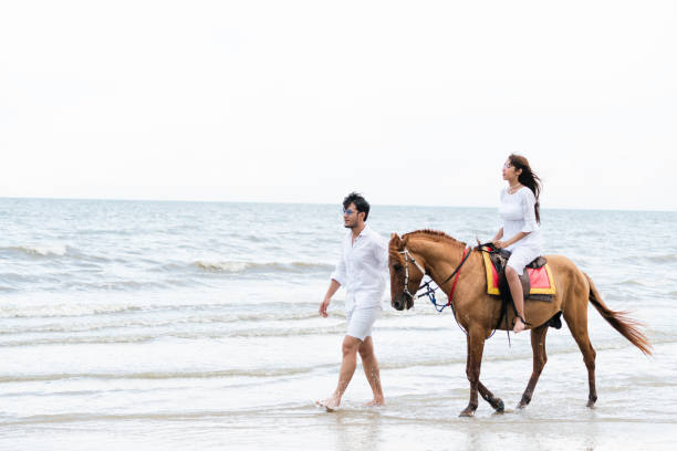 istock Young couple goes horse riding on tropical beach. 1067710038