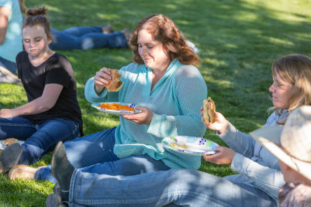 istock Family Group Sitting Eating Lunch in Dappled Light 1067716620