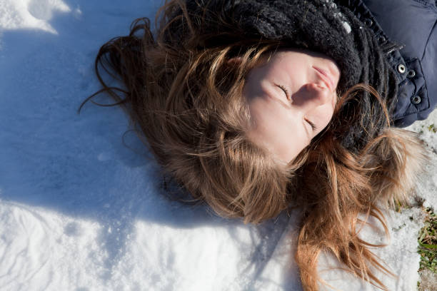 istock Young girl closes her eyes while lying on the snow 1067721344