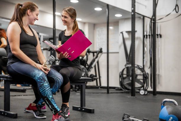 Female Fitness Instructor Going Thru Written Training Program WIth Her Client Female Fitness Instructor Going Thru Written Training Program WIth Her Client. fitness trainer stock pictures, royalty-free photos & images