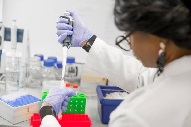 istock Female African Researcher Taking a Sample With Pipette in Laboratory 1067733156