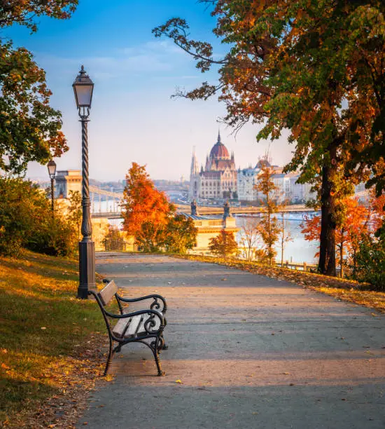 Budapest, Hungary - Romantic sunrise scene at Buda district with bench, lamp post, autumn foliage, Szechenyi Chain Bridge and Parliament at background