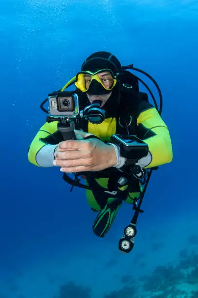 Scuba diver using an action camera to take some underwater photos.
